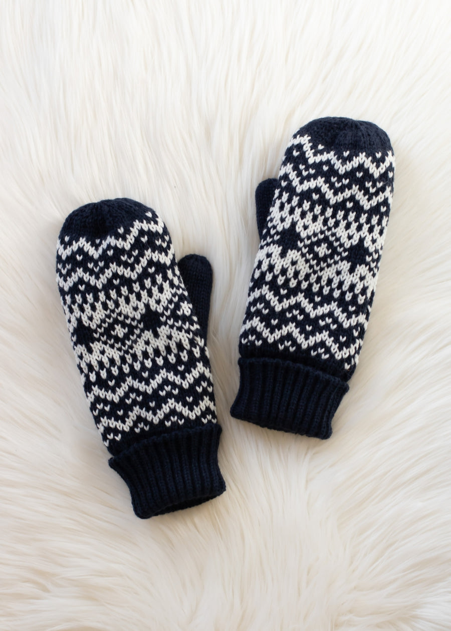 Pair of dark navy and white patterned mittens on a textured white surface