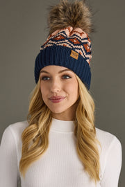 Woman wearing a patterned beanie with a pom-pom on a gray background