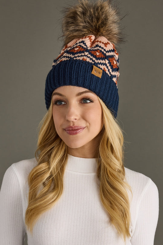 Woman wearing a patterned beanie with a pom-pom on a gray background