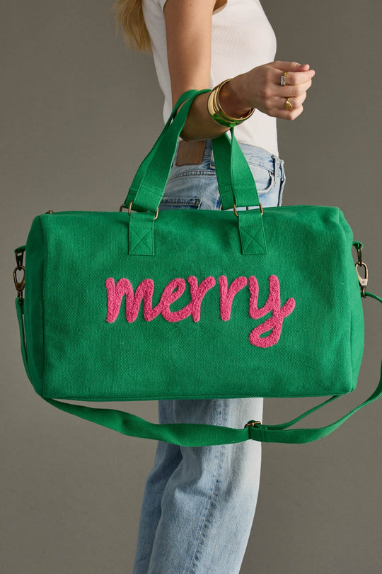 Green bag with 'merry' in pink text held by a person against a gray background