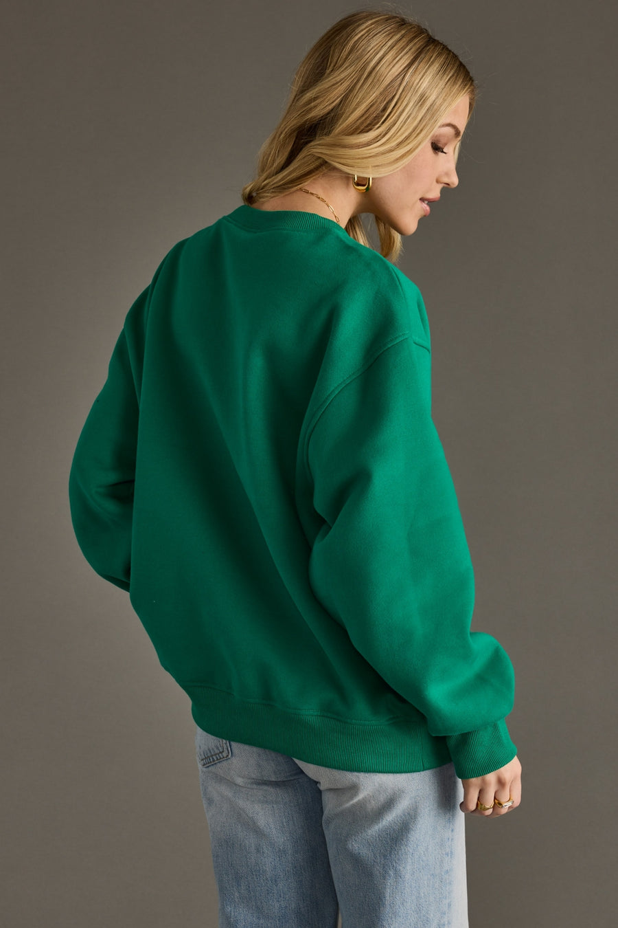 Person wearing a green sweatshirt against a gray background