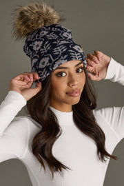 Woman wearing a patterned beanie with a pom-pom on a neutral background