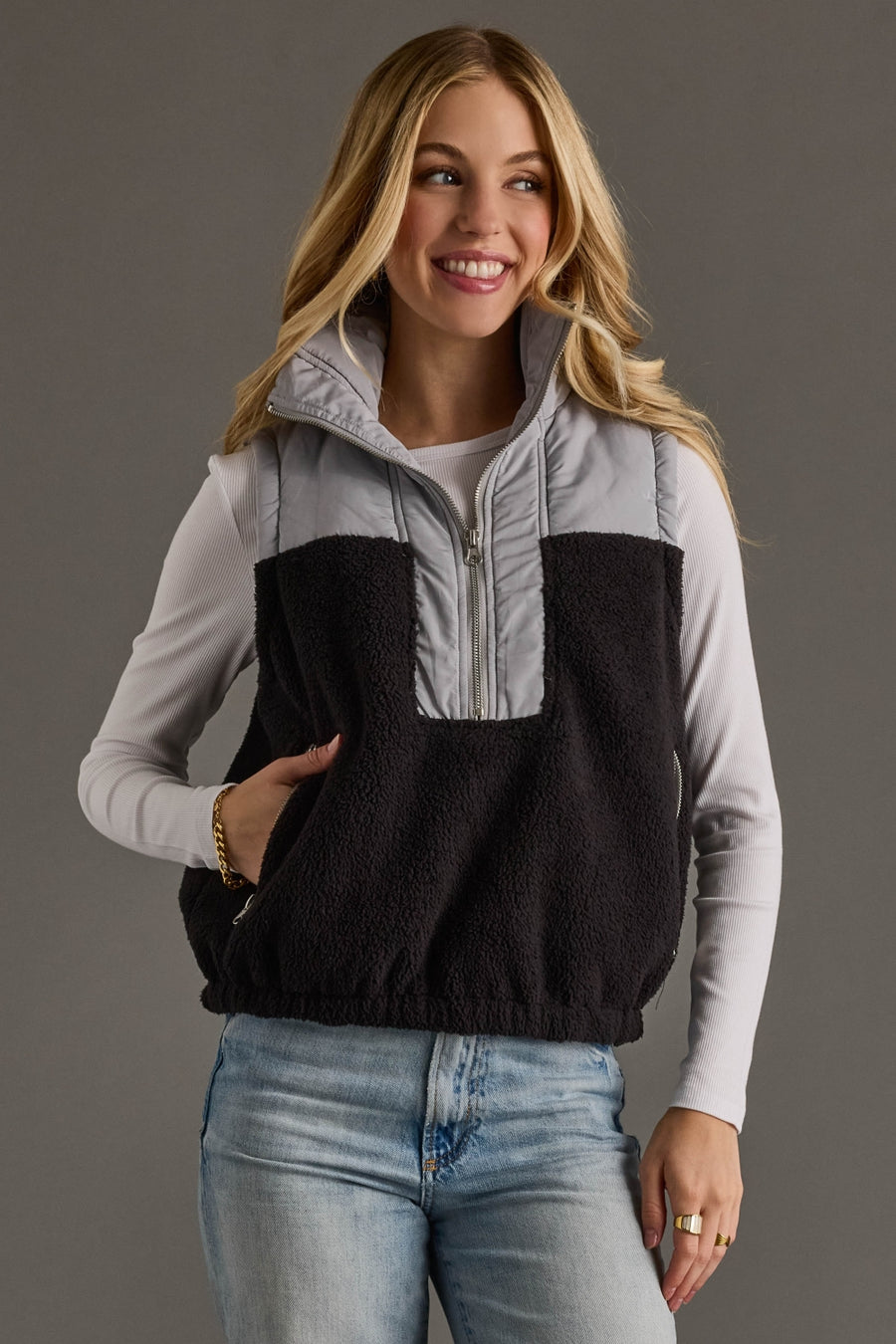 Woman wearing a black and gray half-zip vest against a gray background