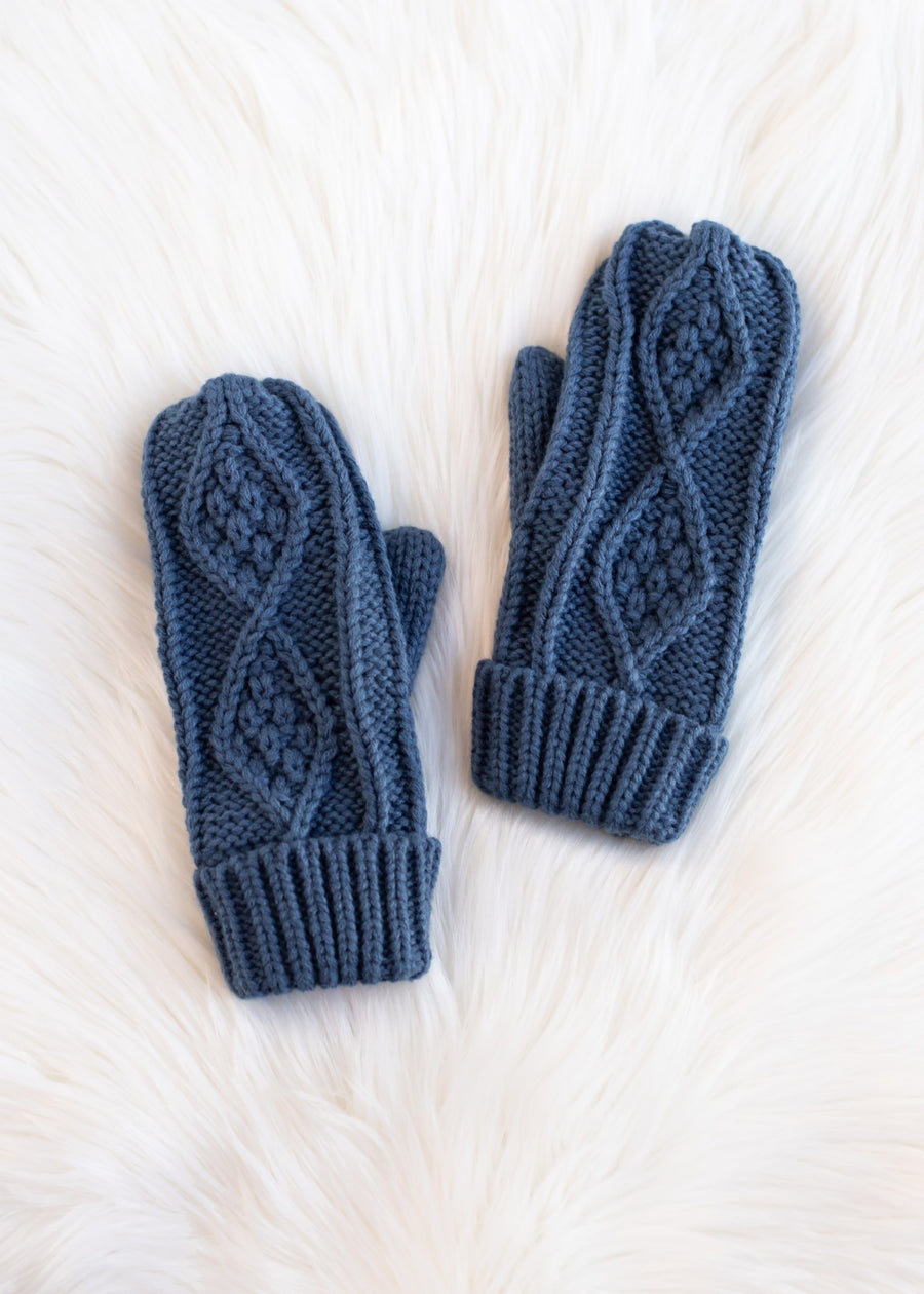 Pair of blue knitted gloves on a white textured surface