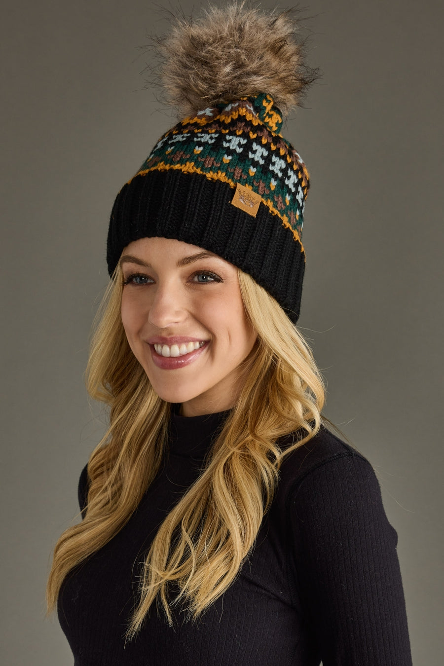Woman wearing a patterned beanie with a pom-pom on a gray background
