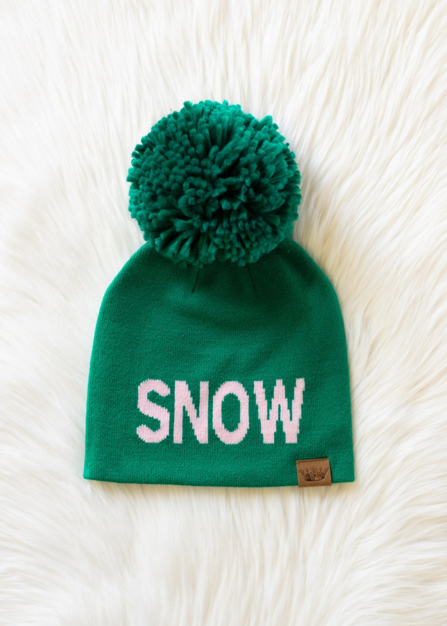 Green beanie with pom-pom and 'SNOW' text on a white fluffy background