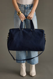 Person holding a navy blue handbag against a neutral background
