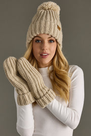 Woman wearing a beige knit beanie and gloves with a plain background