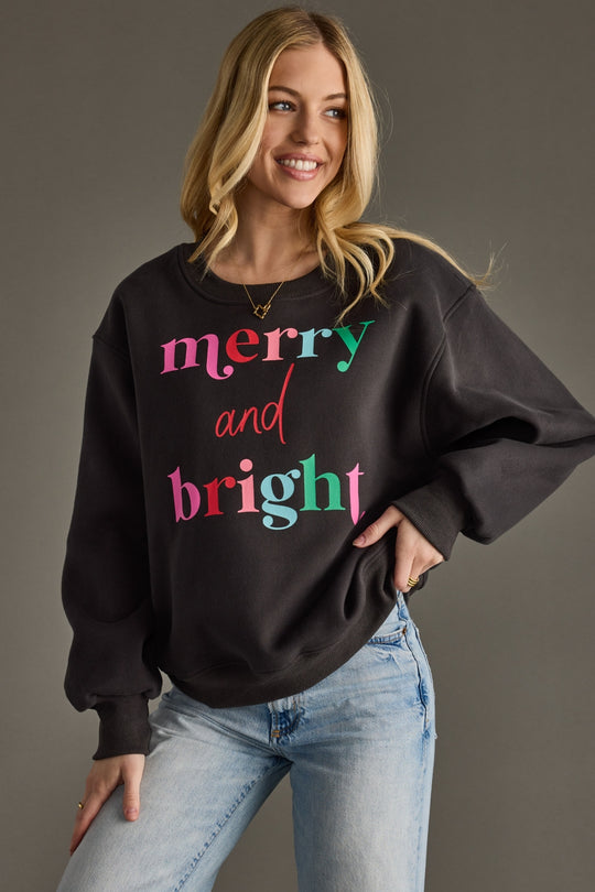 Woman wearing a black sweatshirt with colorful text on a gray background