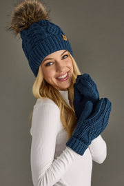Woman wearing a blue knit beanie and gloves against a gray background
