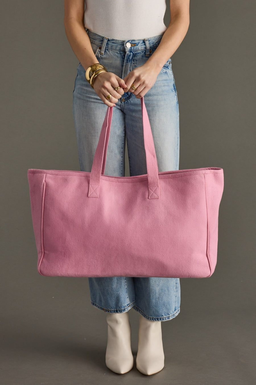 Person holding a pink tote bag against a neutral background