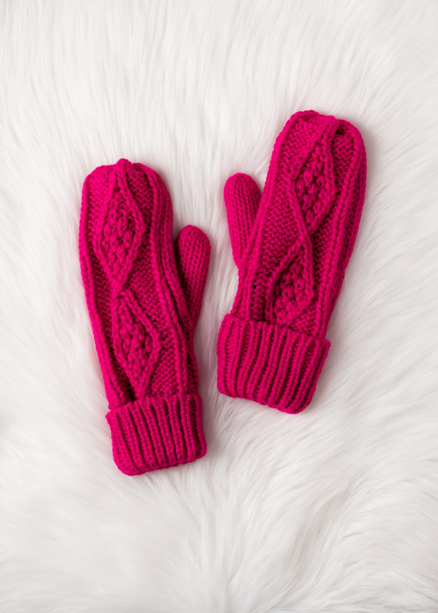 Pair of pink knitted mittens on a white textured surface