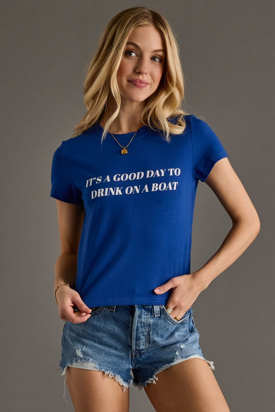 Woman wearing a blue t-shirt with text, standing against a gray background