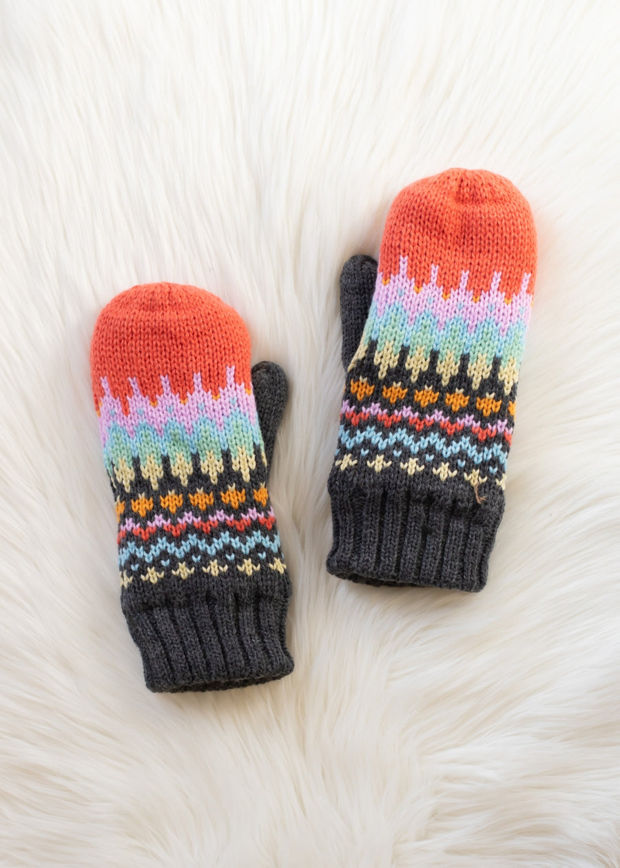 Pair of colorful knitted mittens on a white fur surface