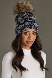 Woman wearing a patterned beanie with a pom-pom on a gray background