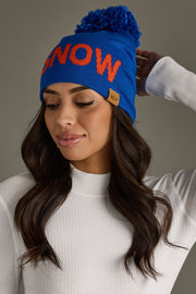 Woman wearing a blue beanie with 'SNOW' in orange on a gray background