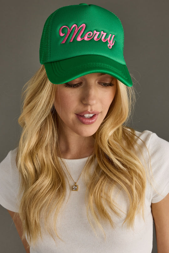 Woman wearing a green cap with 'Merry' text on a gray background