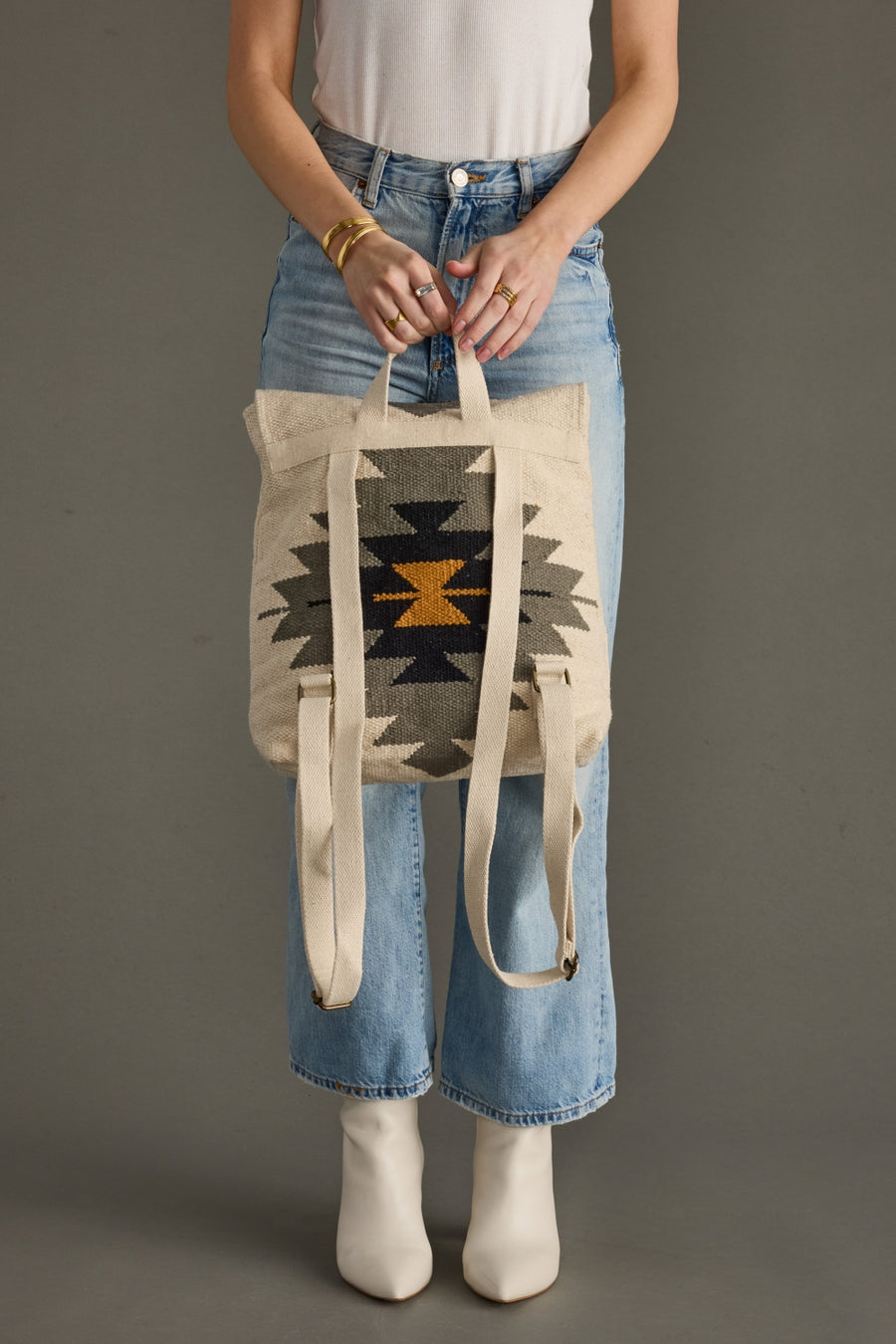 Person holding a tote bag with a geometric pattern against a gray background