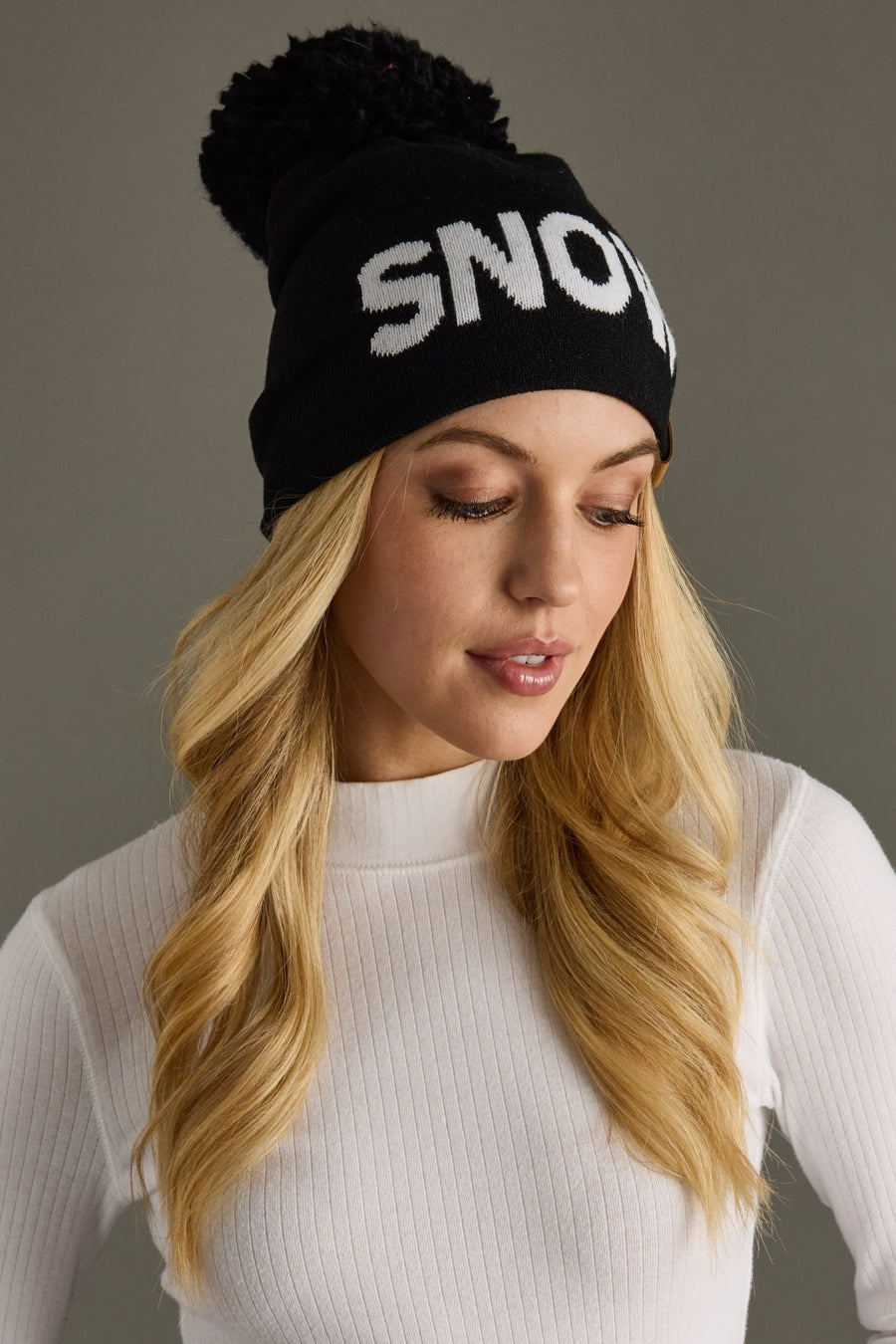 Woman wearing a black beanie with 'SNOW' text on a gray background