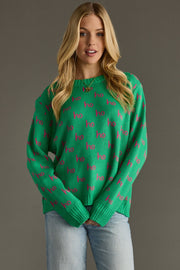 Woman wearing a green sweater with pink patterns against a gray background