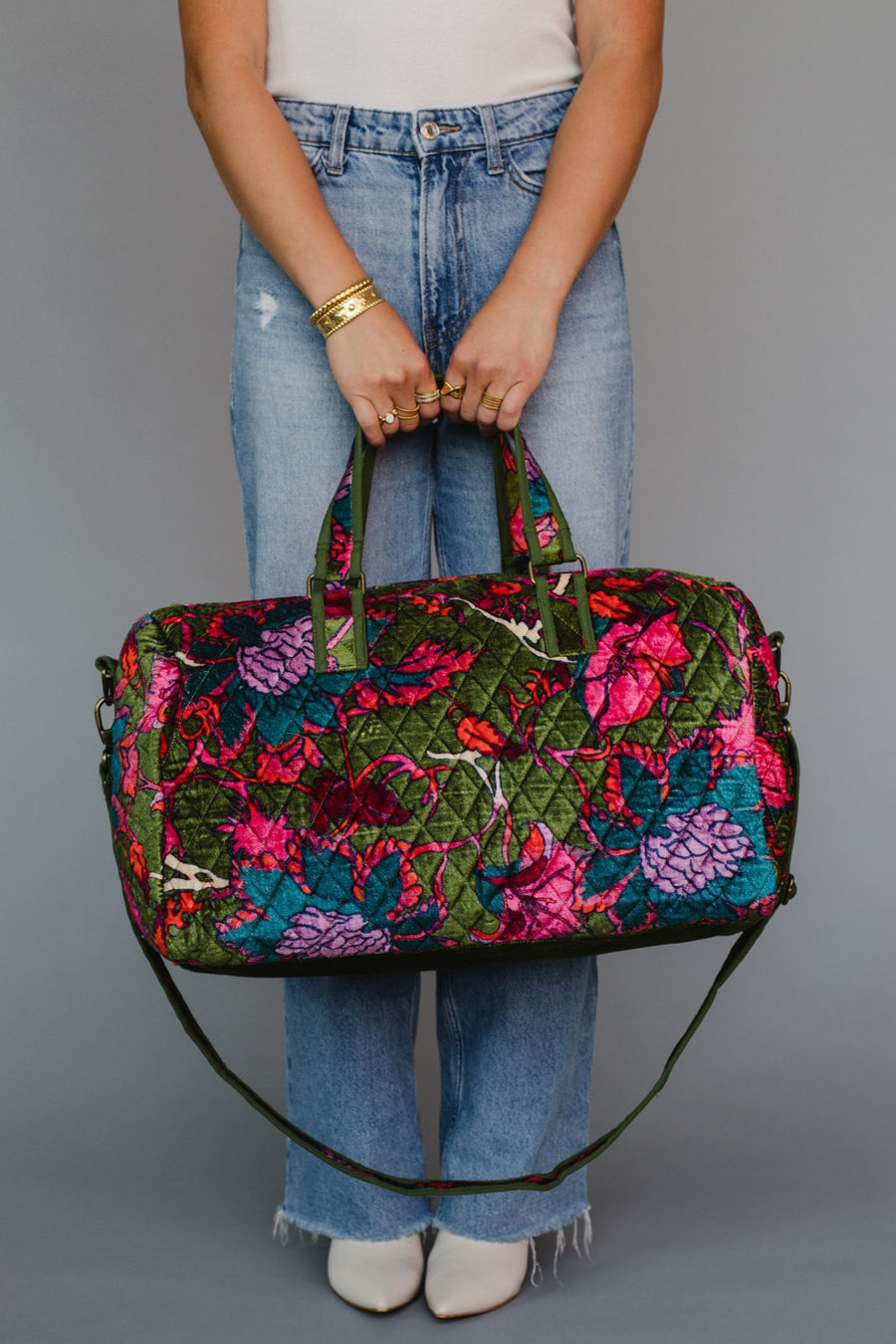 Person holding a colorful floral-patterned handbag against a gray background