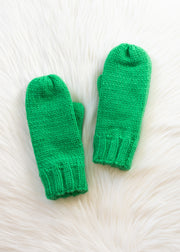 Pair of green knitted mittens on a white textured background
