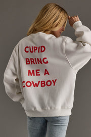 Person wearing a white sweatshirt with red text on the back, standing against a gray background