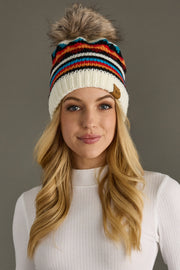 Woman wearing a colorful striped knit beanie against a gray background