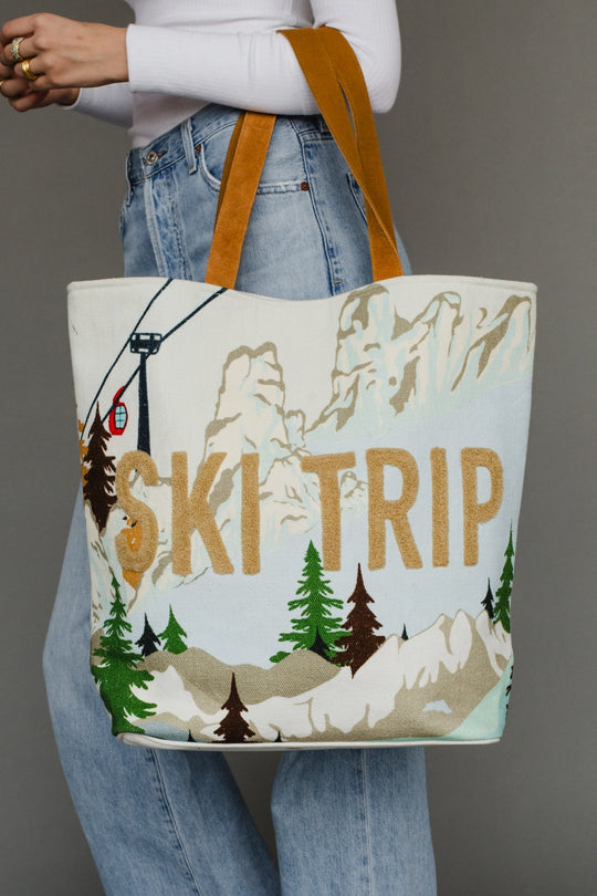 Tote bag with 'Ski Trip' design held by a person wearing jeans and a white sweater.