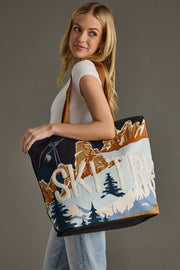 Woman holding a tote bag with 'Ski Trip' design against a gray background