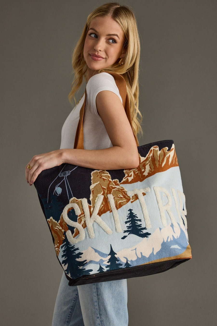 Woman holding a tote bag with 'Ski Trip' design against a gray background