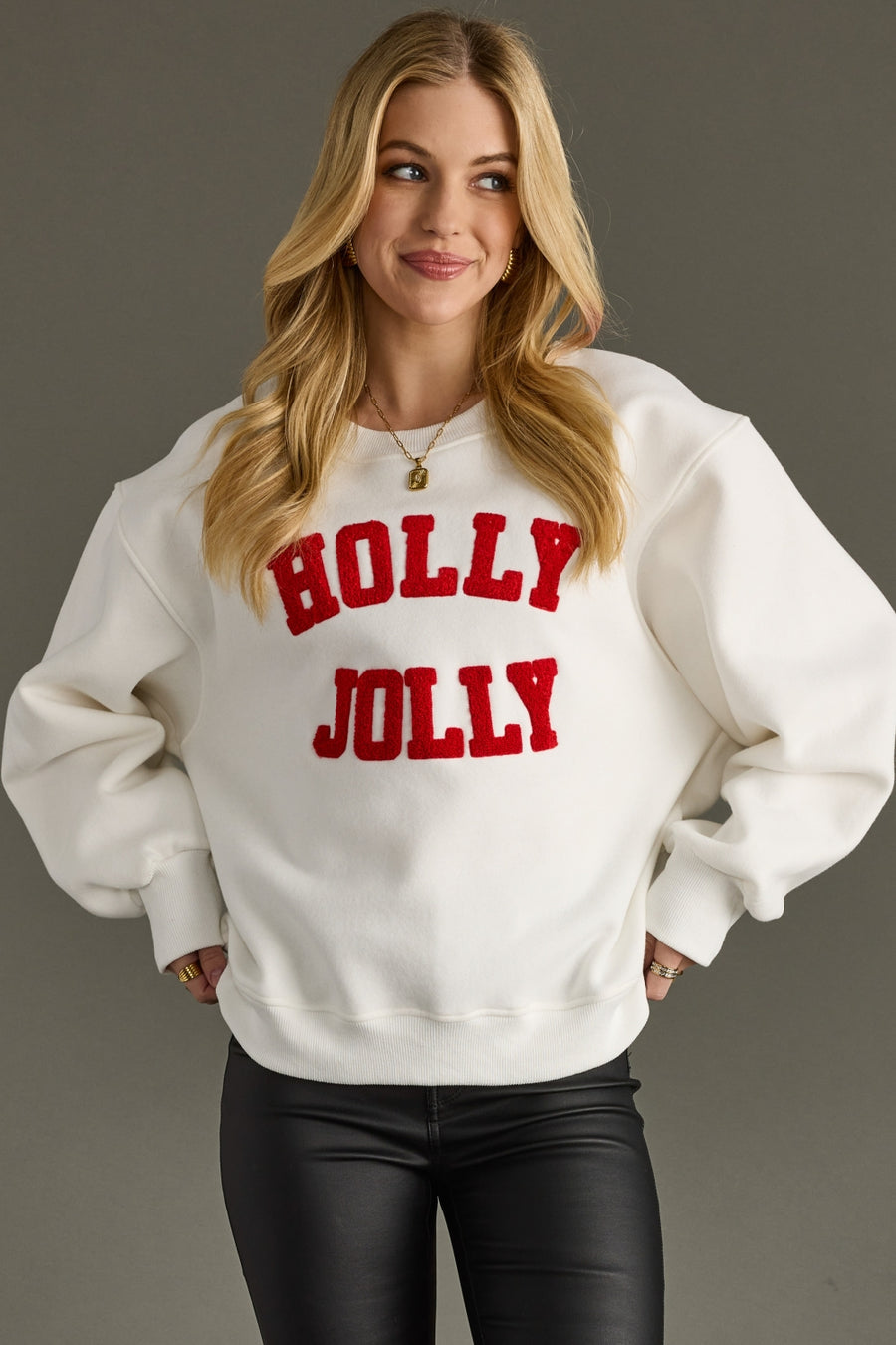 Woman wearing a white sweatshirt with 'Holly Jolly' text on a gray background