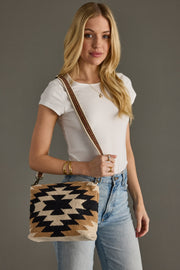 Woman holding a patterned handbag against a plain background