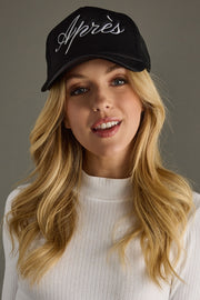 Woman wearing a black cap with 'Apres' text against a gray background