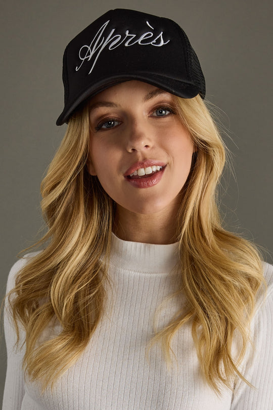 Woman wearing a black cap with 'Apres' text against a gray background