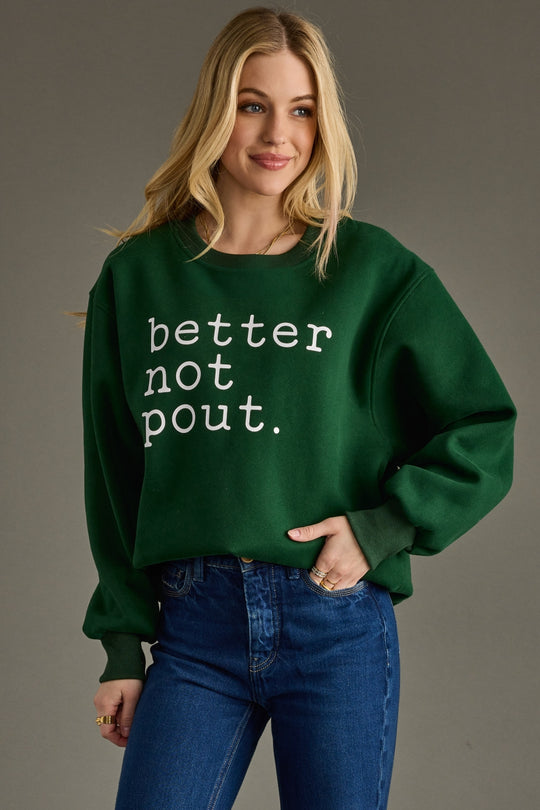 Woman wearing a green sweatshirt with 'better not pout' text on a gray background