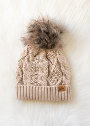 Knitted beanie with fur pom-pom on a white background