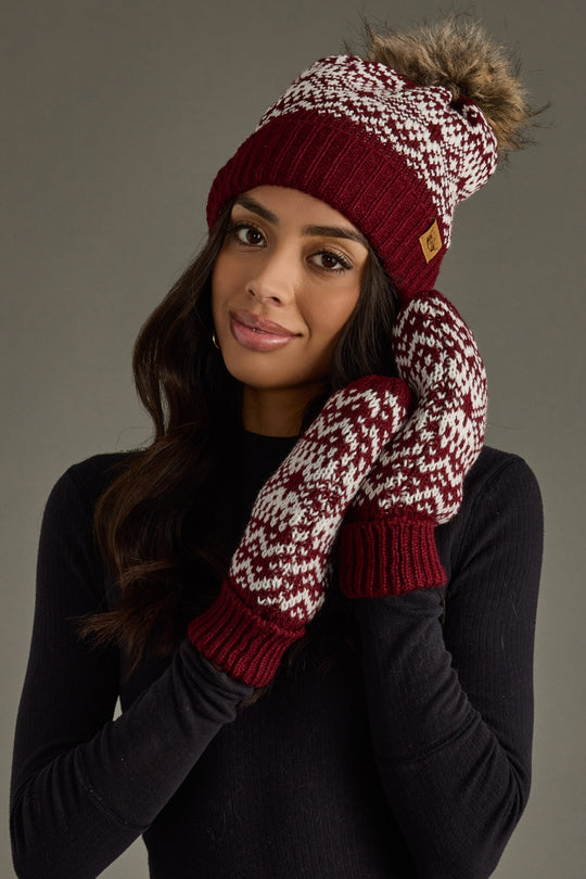 Woman wearing a red and white knit hat and mittens against a gray background