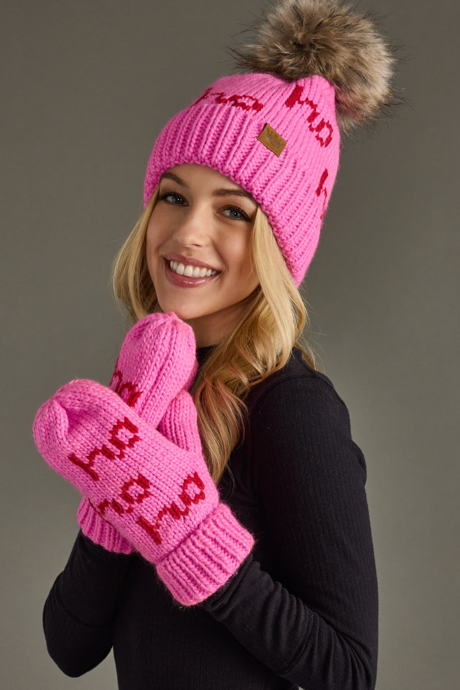 Person wearing a pink knit hat and mittens with text on a gray background