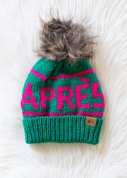 Green knit beanie with pink text and fur pom-pom on a white background