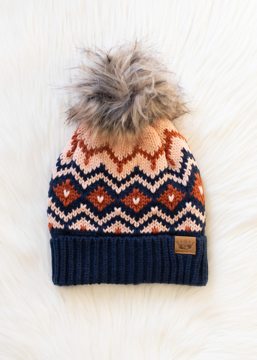 Knit beanie with pattern and fur pom-pom on a white background