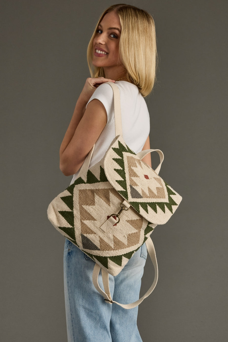 Woman wearing a patterned backpack against a gray background