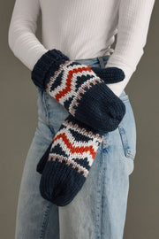 Person wearing navy and patterned mittens with a neutral background