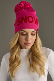 Woman wearing a pink beanie with 'SNOW' text on a gray background