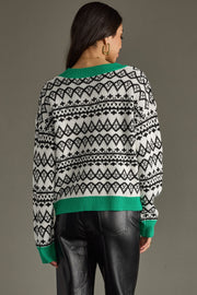 Person wearing a patterned sweater with green trim on a gray background