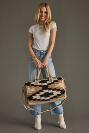 Woman holding a patterned handbag against a gray background
