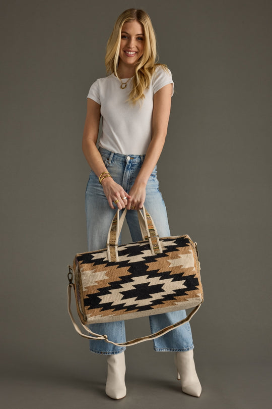 Woman holding a patterned handbag against a gray background