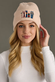Woman wearing a blush beanie with embroidered designs on a gray background
