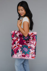 Woman holding a colorful floral tote bag against a gray background