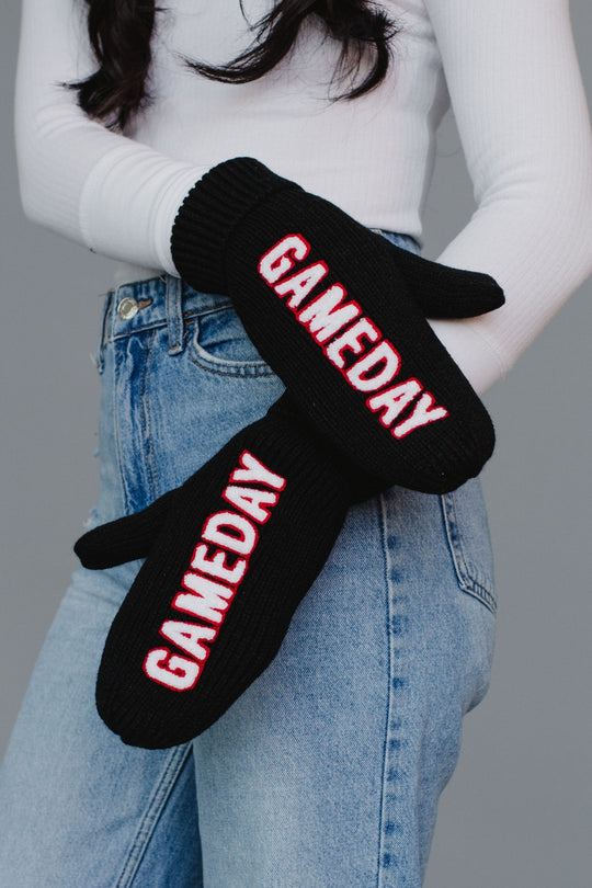 Black gloves with 'GAMEDAY' text worn by a person against a gray background